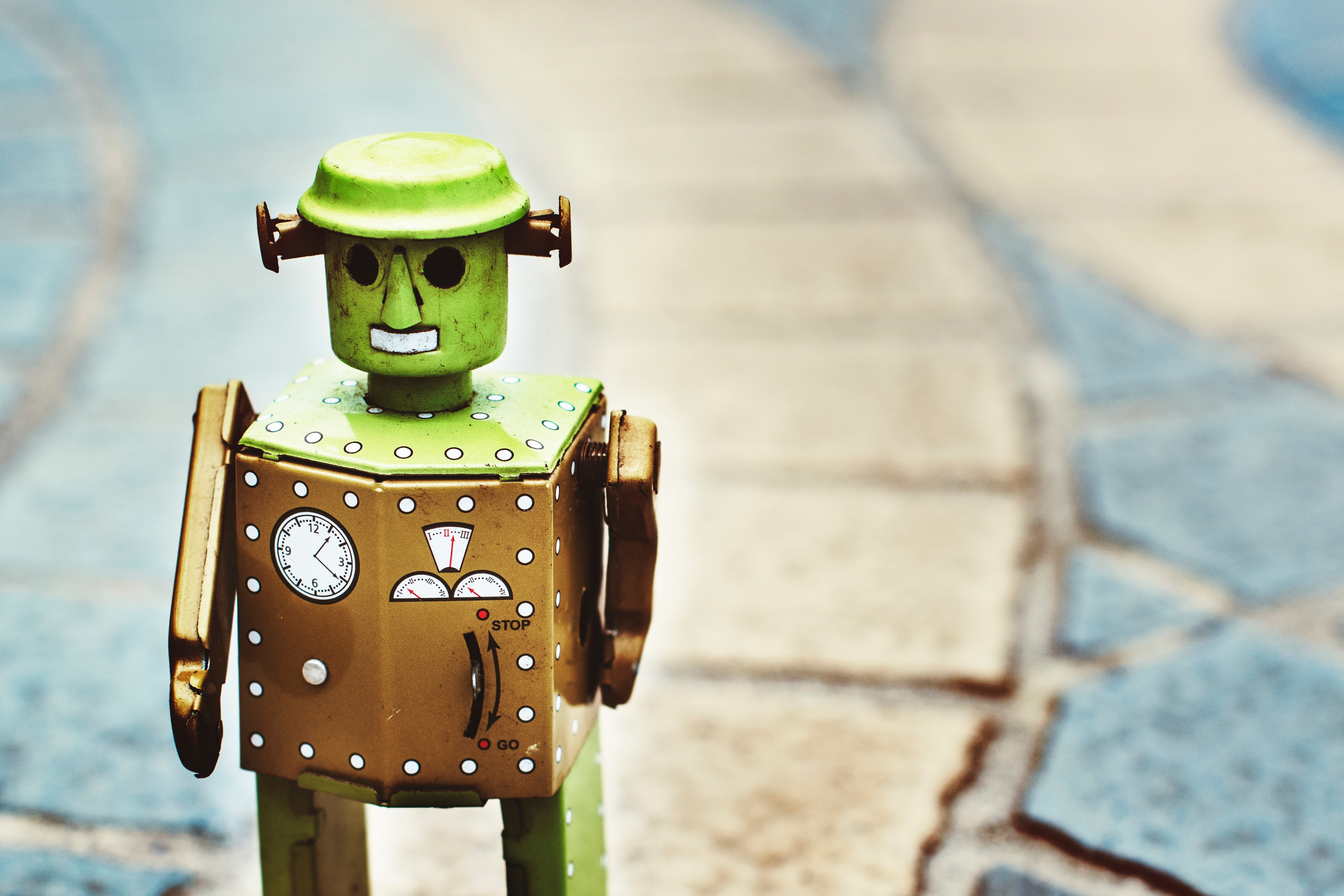 Vintage tin toy robot standing on a stone path, illustrating outdated assumptions about what a bot looks like in survey research